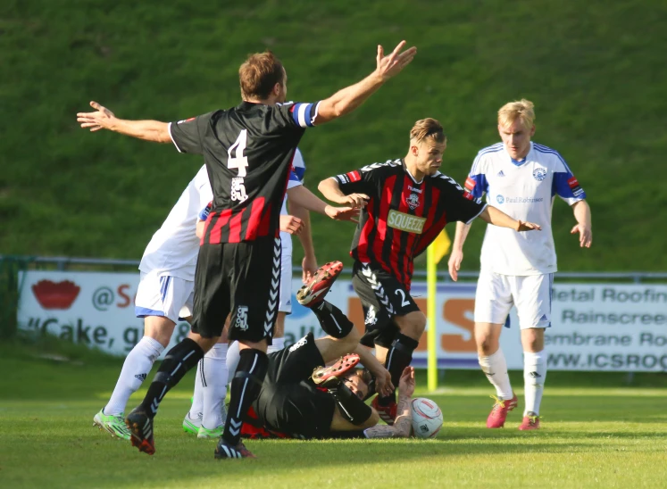 two teams of soccer players attempt to stop the ball as the opposing team tries to tackle it