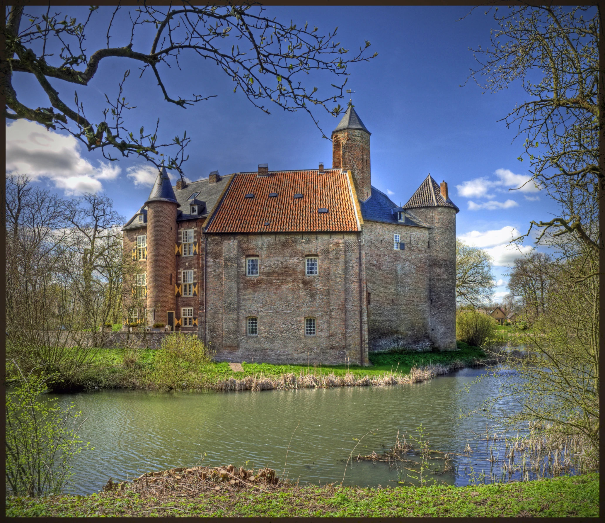 a large brick building with many spires in a field near water