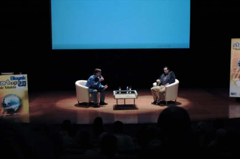 two men in a business meeting in front of a large screen