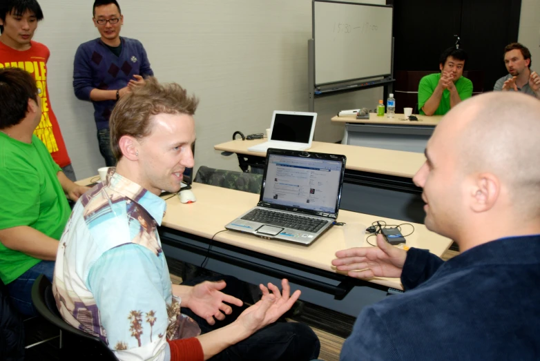 several men sitting at a table with laptops