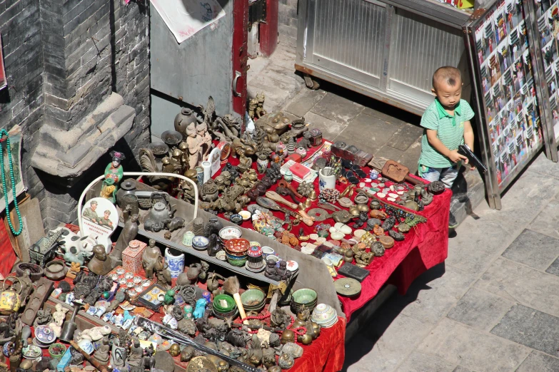 a young child standing in front of a table with lots of ons and glass objects