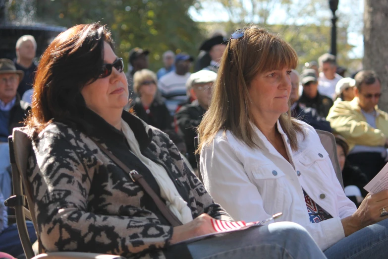 two women sitting together in front of an audience