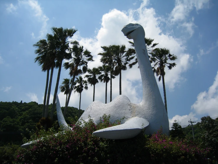 a sculpture of a dinosaur is outside in front of some trees