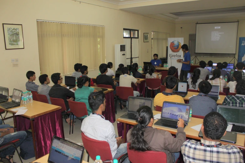 group of people in chairs using laptops at desks