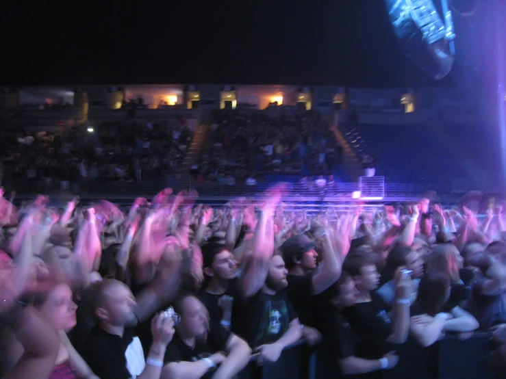 a large group of people at a concert, their hands in the air