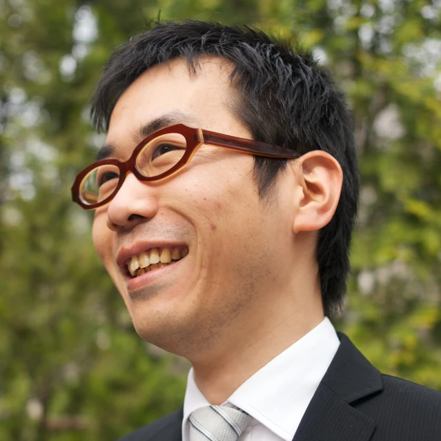 an asian man smiles and wears a suit and tie