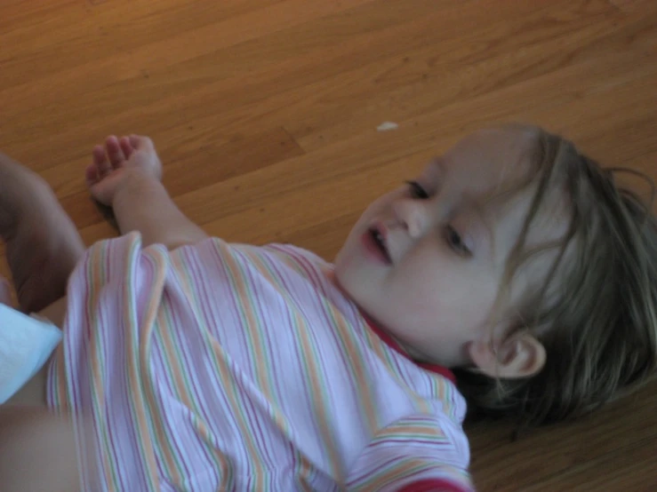 a small girl laying down on a wood floor