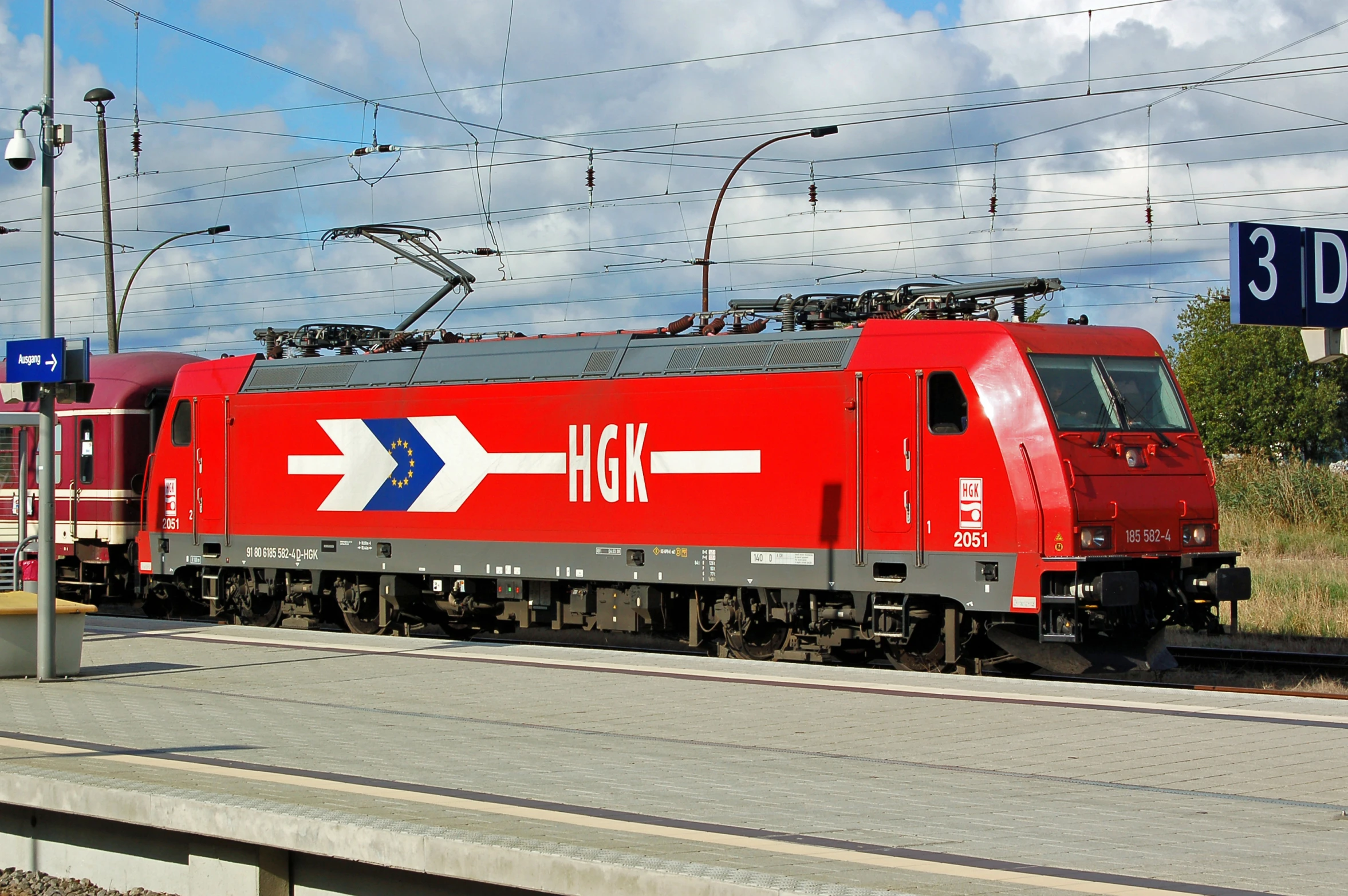 a red train pulling many carts down a track