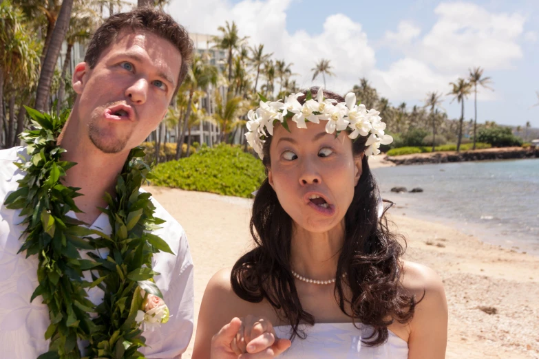 a man and a woman wearing leis next to the water