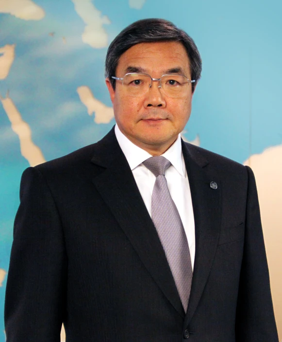 a man wearing glasses and a suit in front of a map