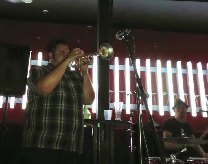 the man plays the trumpet in front of his band