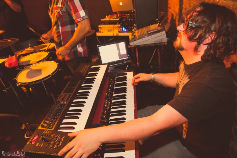 a man with glasses plays music on a musical keyboard