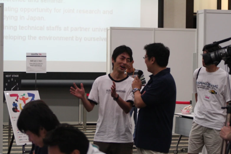 three men talking while a speaker has his hands in the air