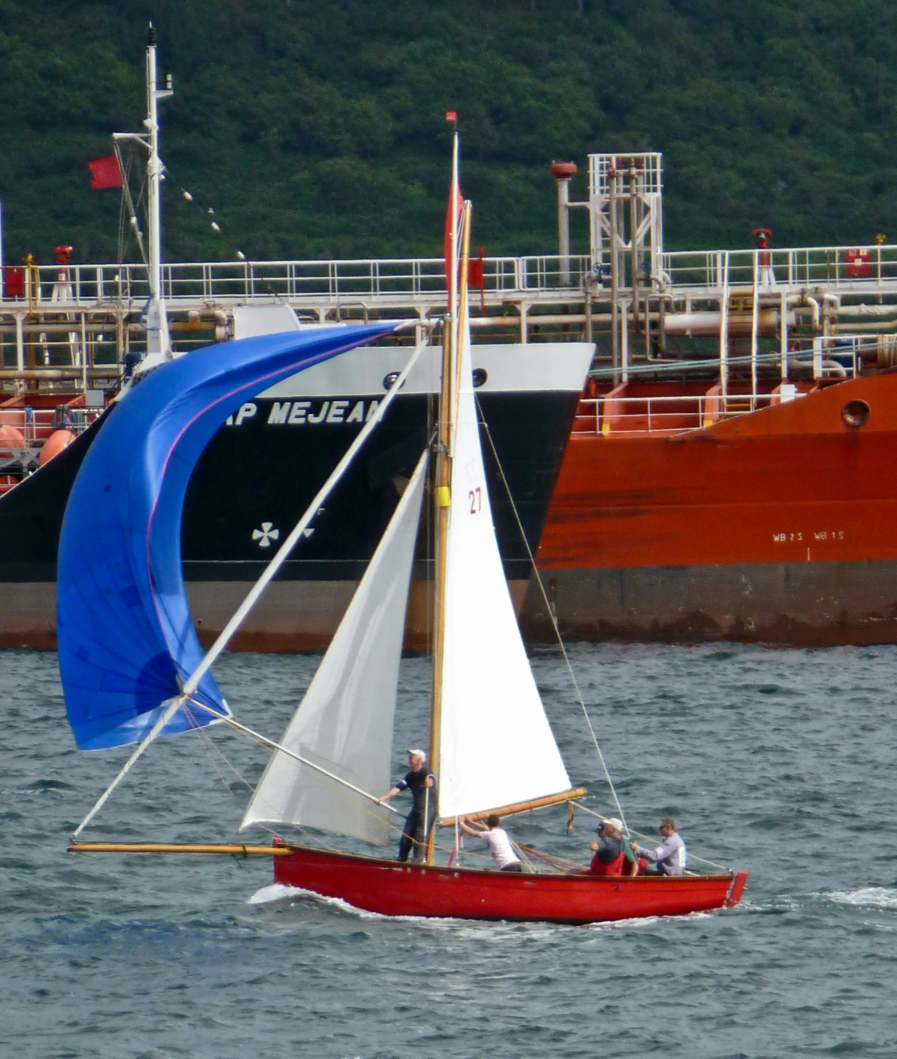 a red sailboat with white and blue sails