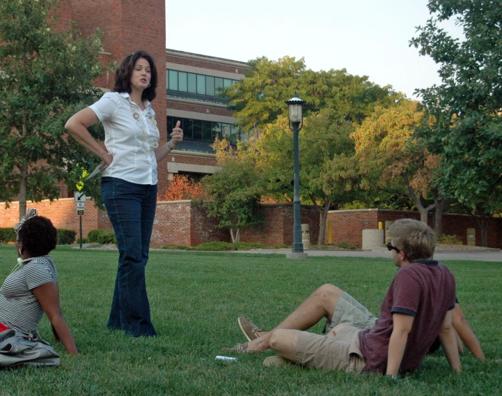 two young men and a woman sitting on the grass