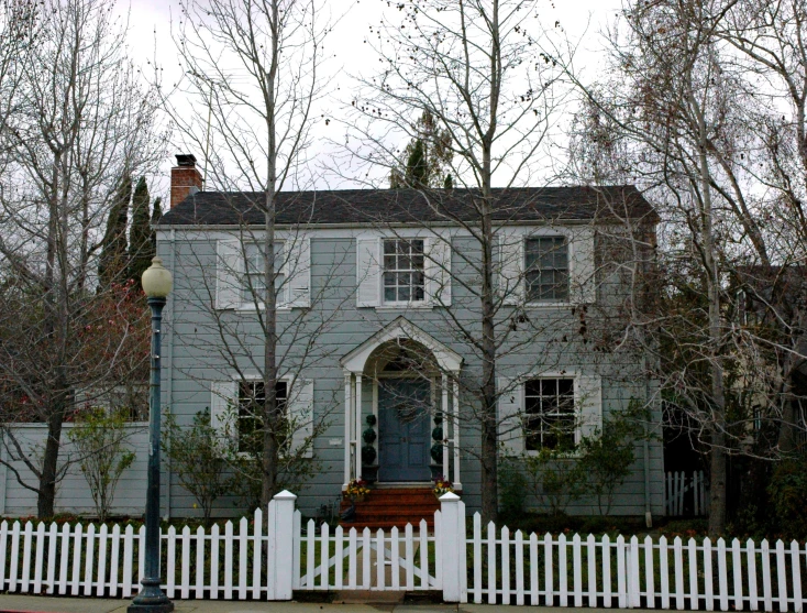 a white picket fence sits in front of a grey house