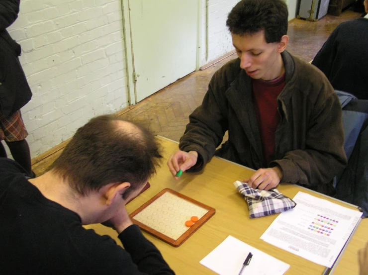 people sitting at a table and writing on a sheet