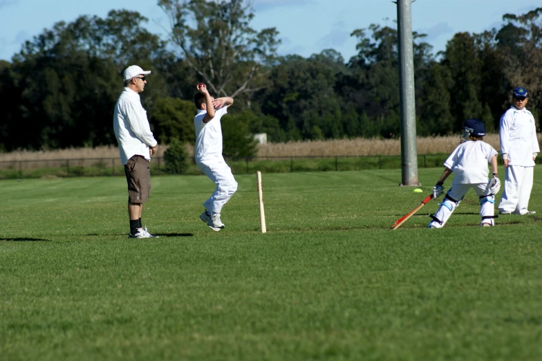 a group of children playing cricket in a grassy field