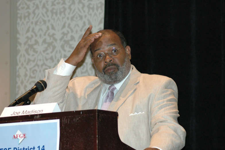 a man is holding his head in front of a microphone