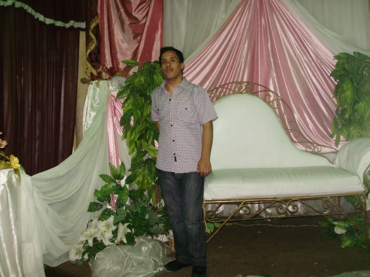 a man standing next to a couch covered in lush greens