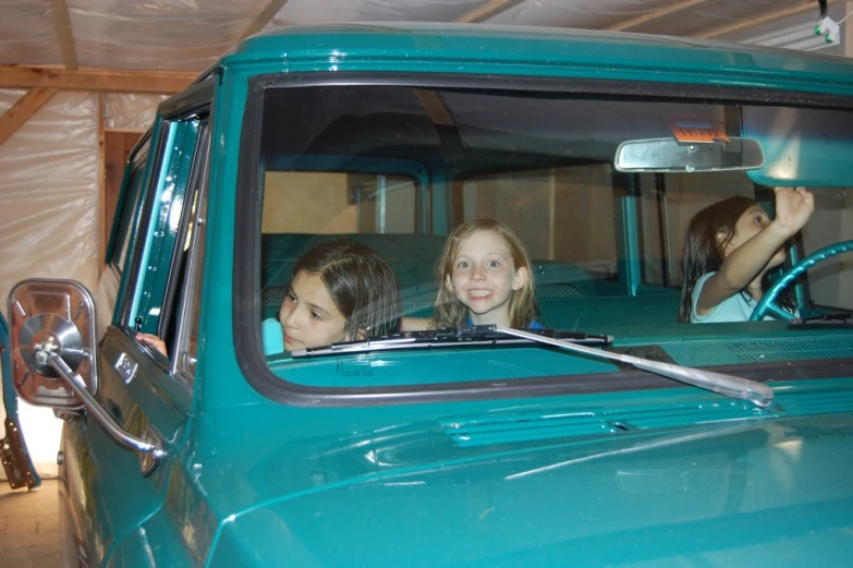 two girls are sitting in the cab of an old truck