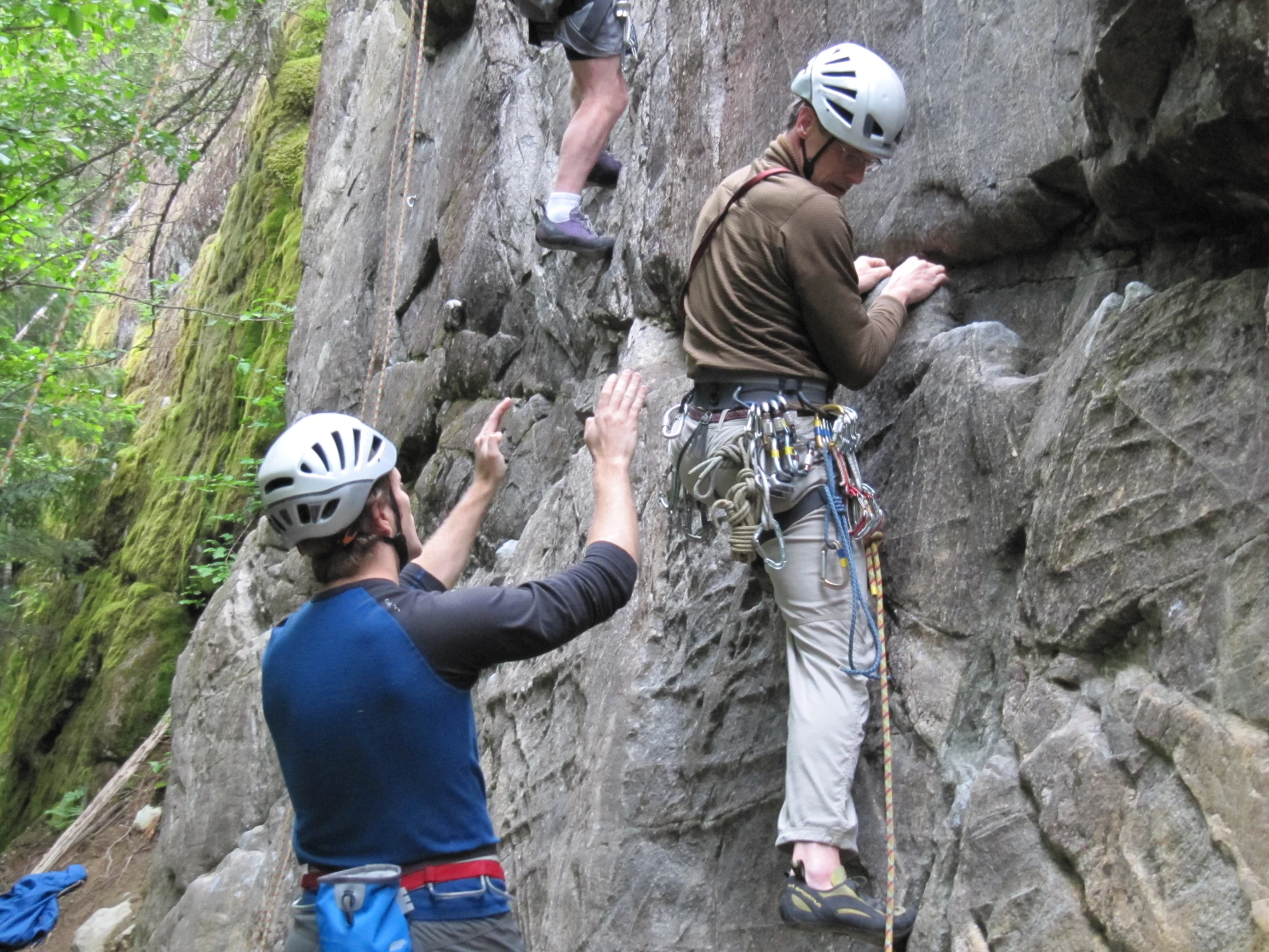 two men climb up rocks with their hands in the air