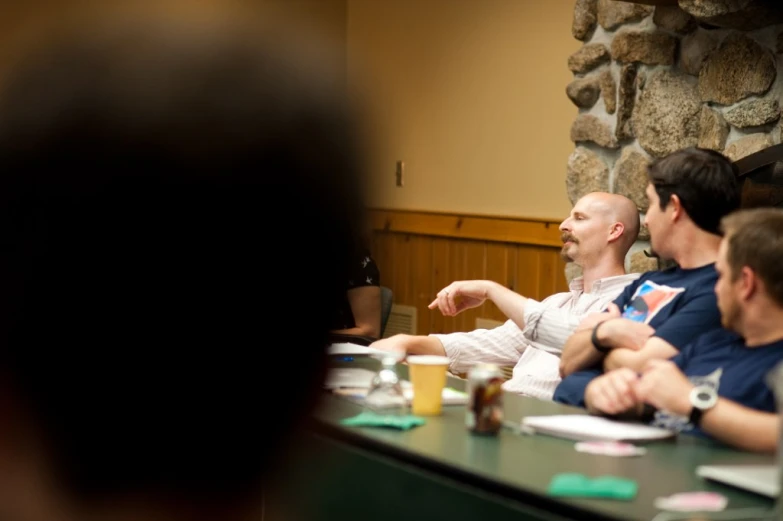 the group of people are sitting at a long table