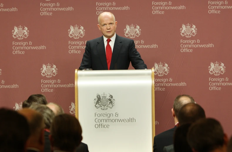 a man is speaking at a podium in front of a crowd