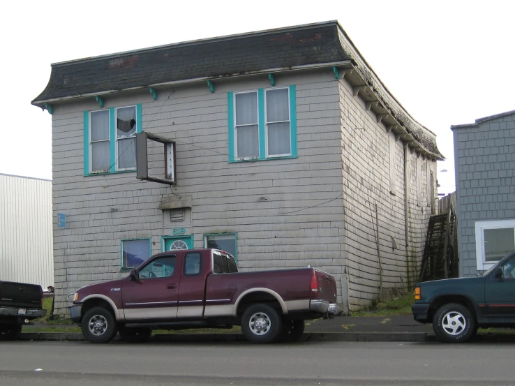 an old red truck sitting next to a house