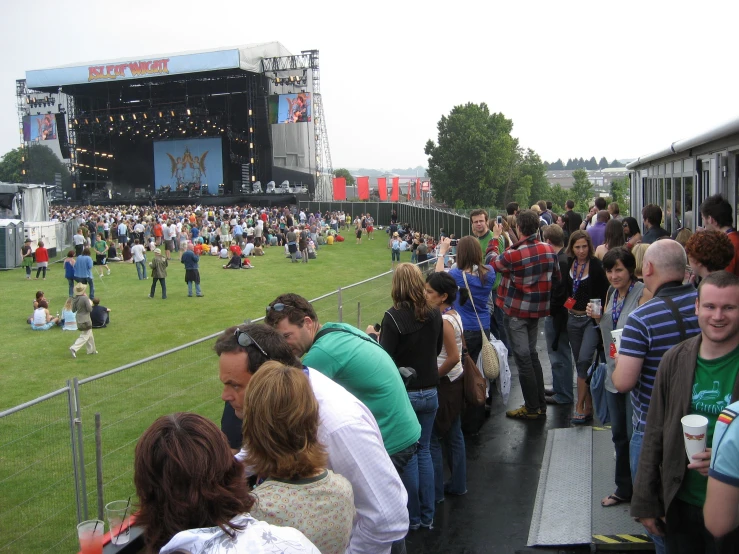 a crowd is waiting at an outdoor concert on the grass