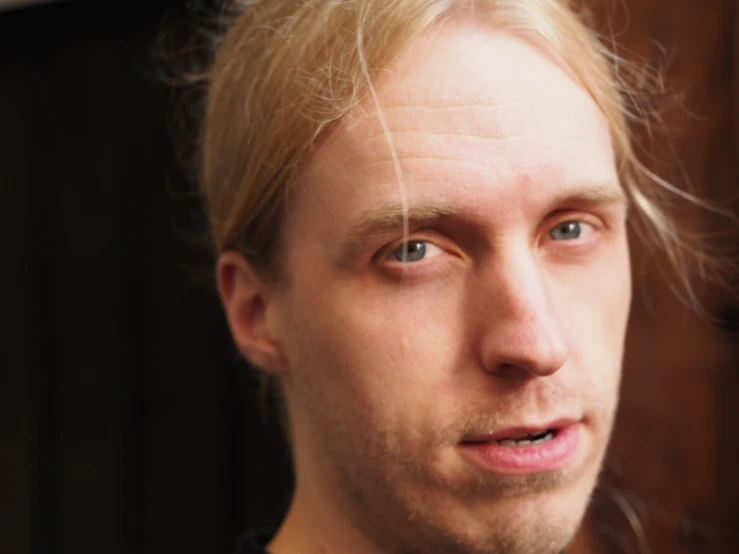a man with blond hair stares into the camera