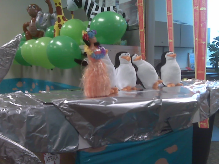 a group of plastic penguins on a foil table with balloons