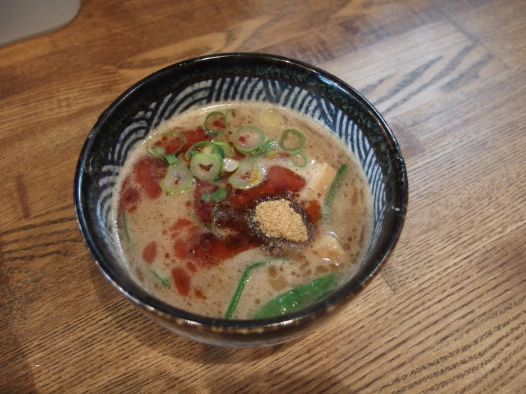 a bowl filled with food and garnishment sitting on a wooden table