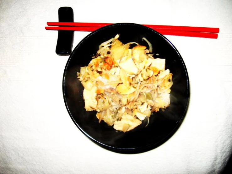 chop sticks on white surface with black plate and red and white table cloth