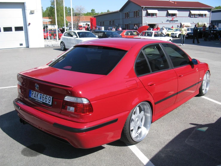 the red bmw coupe is parked in the parking lot