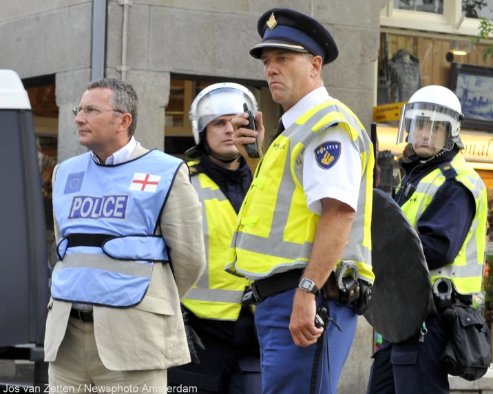 three policemen in uniform and helmets standing near each other