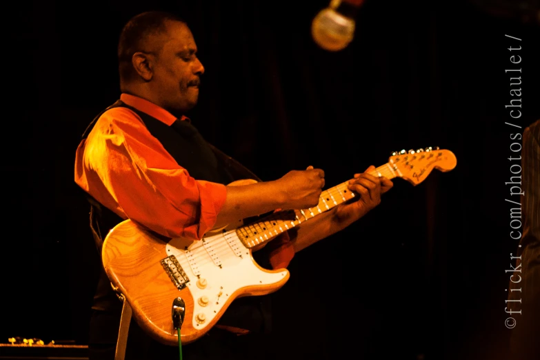 man holding a guitar while standing on a stage