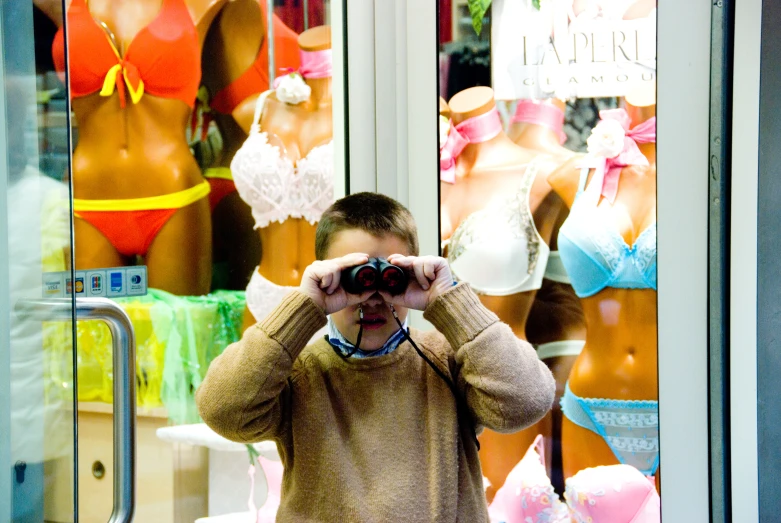 a man looking through binoculars at a mannequin's