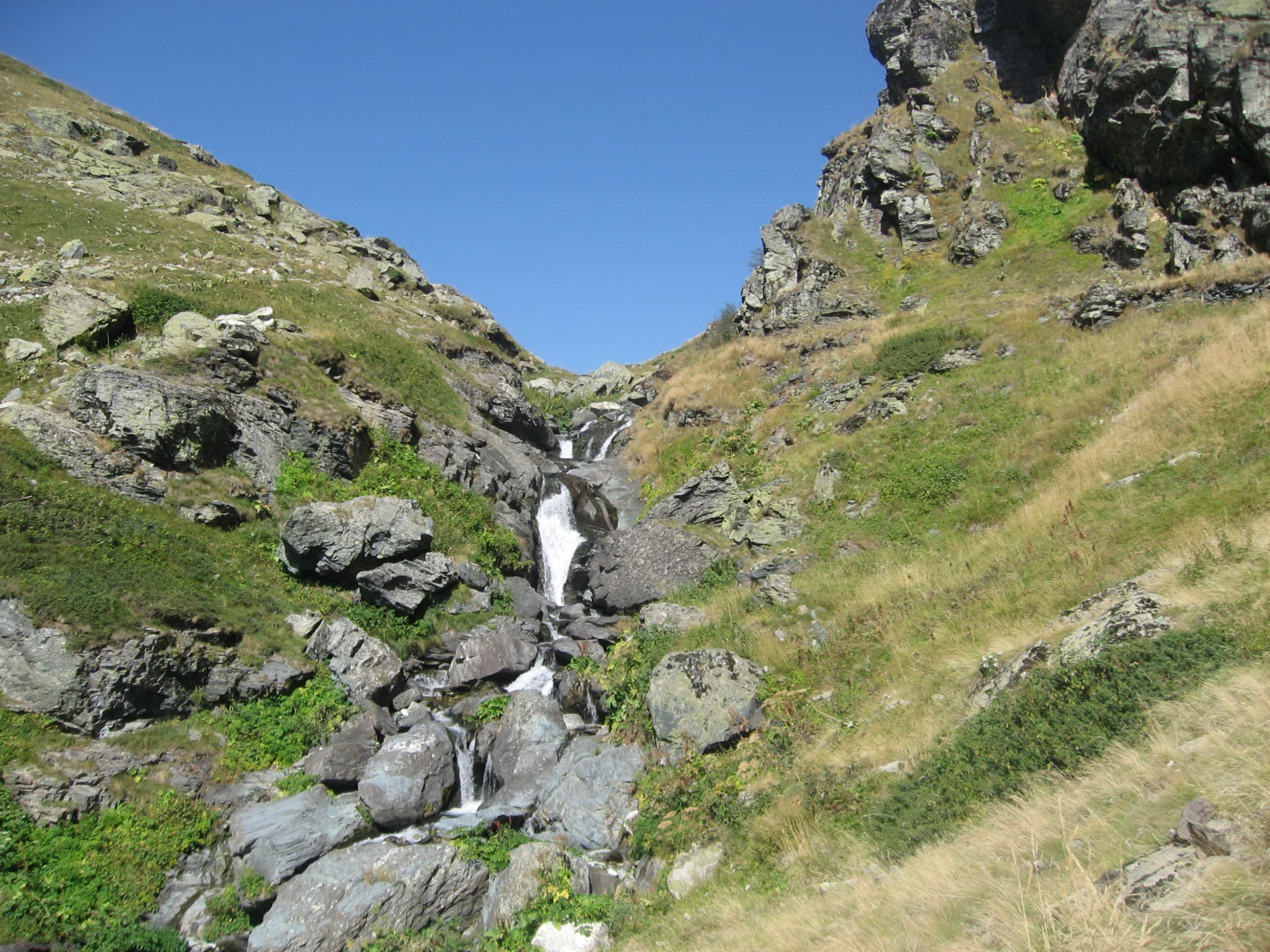 two waterfall on a steep hill under a blue sky