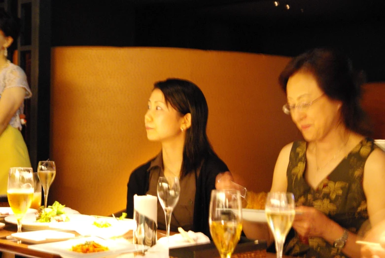 three women at a dinner table, one has wine glasses