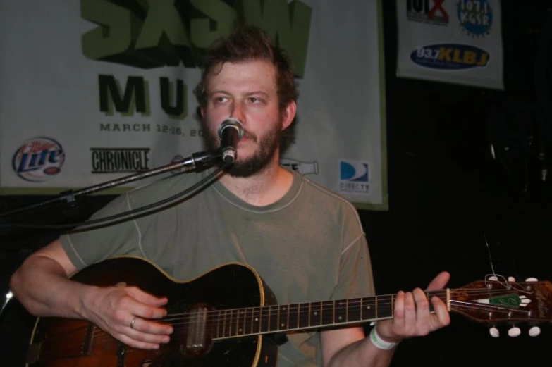 a man singing into a microphone while holding an acoustic guitar