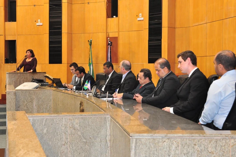 men and women sitting around tables in front of wood panels