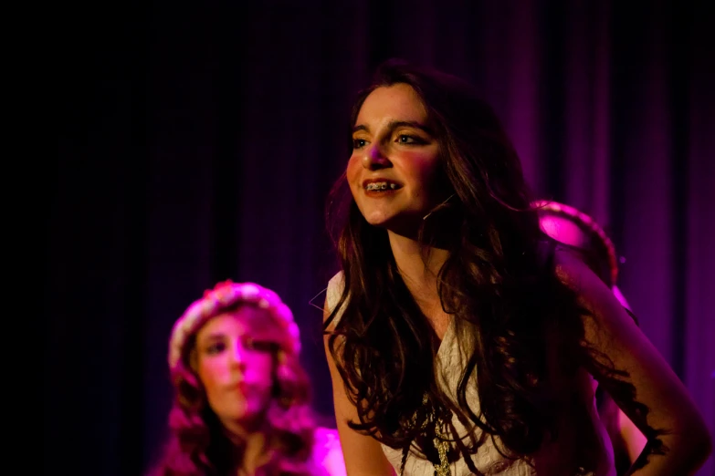 two woman at an event are talking on a stage