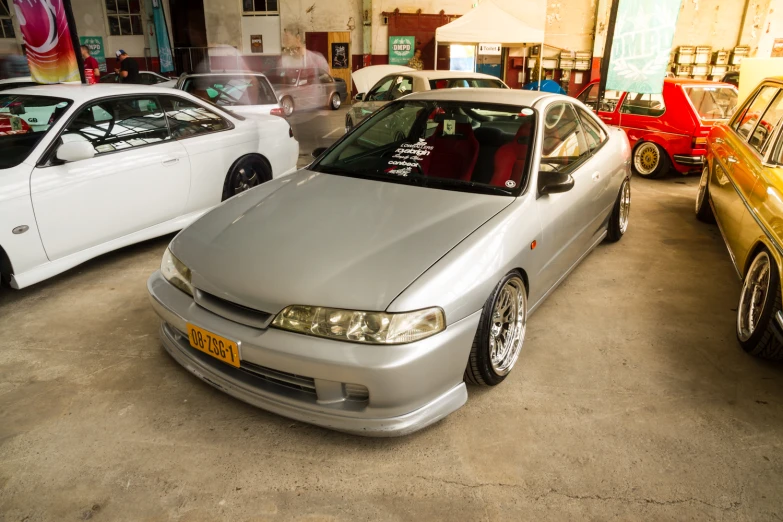 a white car in a garage with other cars behind it