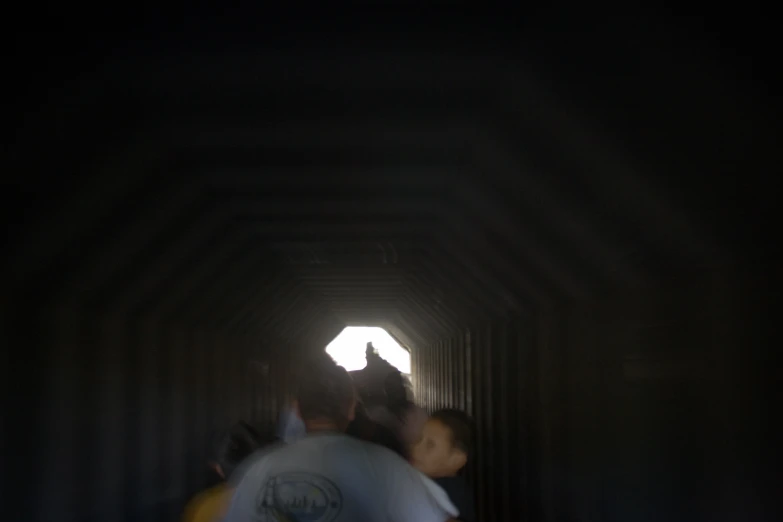 a group of people walking down a long tunnel with one person pointing the other direction