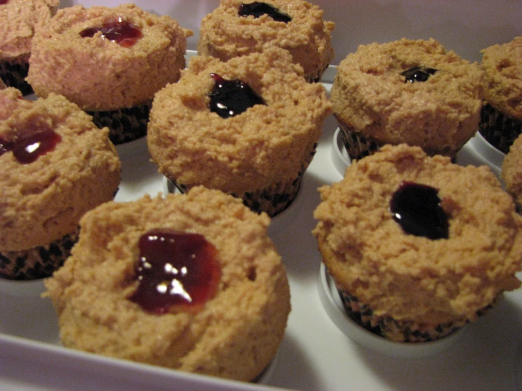 an array of muffins with jelly and cherry sauce in the middle