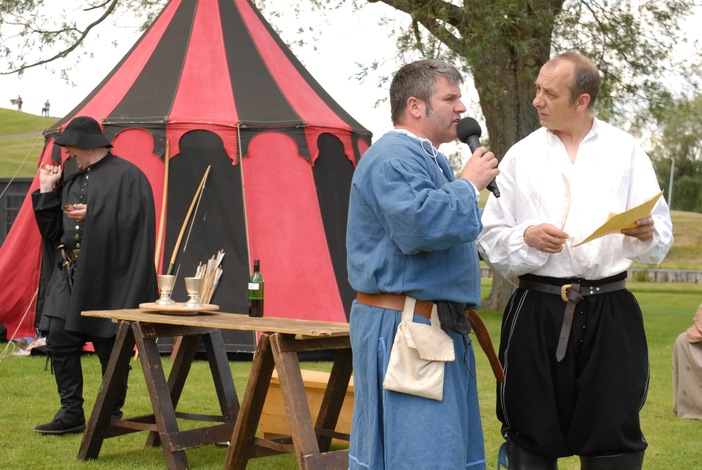 two men are having a conversation outside under a tent