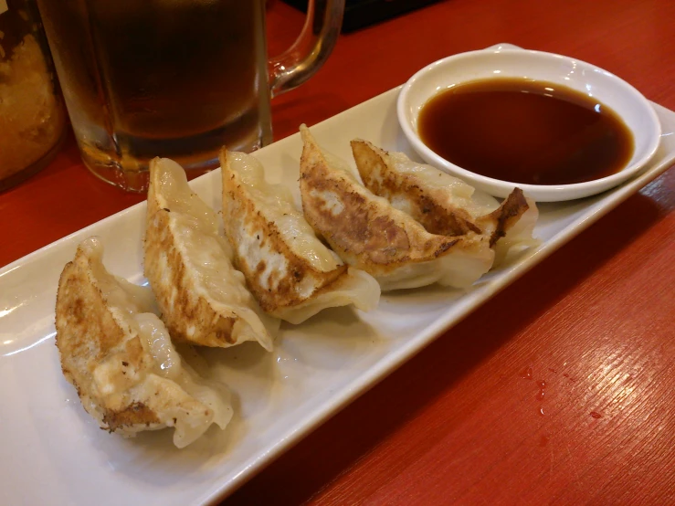 a plate on a table with several dumplings and dipping sauce