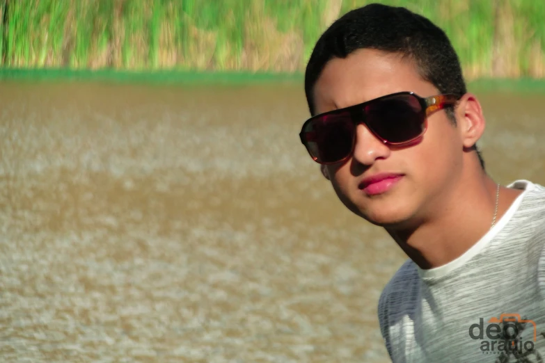 the young man wearing sunglasses looks ahead on the beach