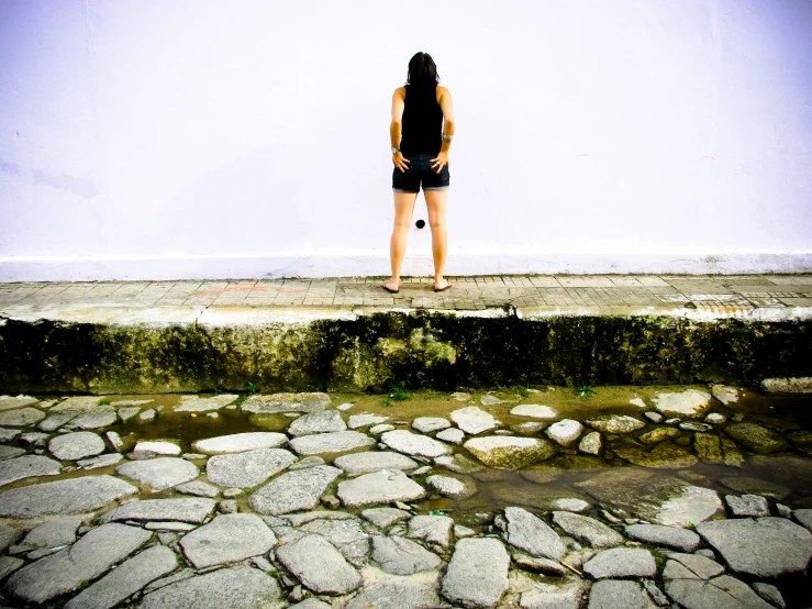a young woman looks out from behind a wall